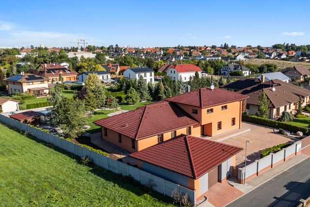 Letecký pohled na dům a oplocený pozemek v zástavbě obce
