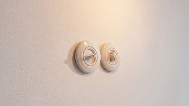 Detail porcelánových vypínačů na bílé stěně